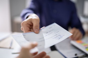 1191080753 Mann übergibt Scheck an Kunden
